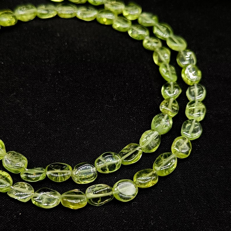 May include: A strand of light green oval-shaped beads. The beads are translucent and have a slightly frosted appearance.