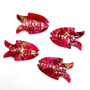 May include: Four red and gold fish shaped carvings made of gemstone. The fish are carved with intricate details and have a shiny, polished finish.
