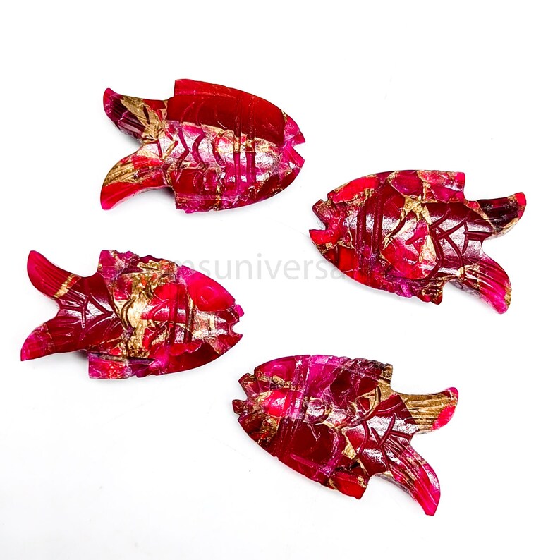 May include: Four red and gold fish shaped carvings made of gemstone. The fish are carved with intricate details and have a shiny, polished finish.