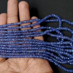K&ouml;nnte beinhalten: Eine Str&auml;hne blauer Edelsteinperlen, wahrscheinlich Saphire, mit facettierter Oberfl&auml;che. Die Perlen sind klein und gleichm&auml;&szlig;ig in der Gr&ouml;&szlig;e, was einen zarten und eleganten Look erzeugt.