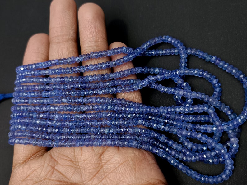 K&ouml;nnte beinhalten: Eine Str&auml;hne blauer Edelsteinperlen, wahrscheinlich Saphire, mit facettierter Oberfl&auml;che. Die Perlen sind klein und gleichm&auml;&szlig;ig in der Gr&ouml;&szlig;e, was einen zarten und eleganten Look erzeugt.