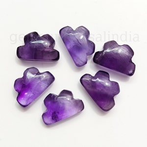 May include: Six amethyst cloud-shaped gemstones are arranged in a circle on a white surface. The gemstones are a deep purple colour with lighter purple and white inclusions. The clouds have a smooth, polished finish.