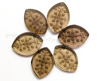 May include: Six brown, carved gemstone cabochons in a leaf shape with a floral design.