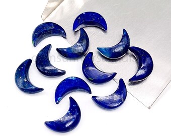 May include: A collection of ten crescent moon shaped lapis lazuli gemstones. The stones are a deep blue color with flecks of gold pyrite.