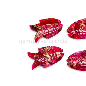 May include: Four carved ruby fish pendants with gold accents. The fish are carved in a detailed, intricate style. The ruby is a deep red color.