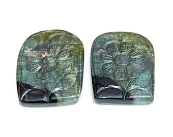 May include: Two carved green and black gemstone cabochons with a flower design.
