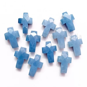 Puede incluir: Diez abalorios de cruz de piedra preciosa azul claro. Las cruces son facetadas y tienen una forma ligeramente irregular.