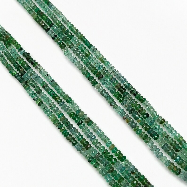 Pode incluir: Um fio de contas de pedras preciosas verde esmeralda, com um formato facetado ligeiramente irregular. As contas s&atilde;o enfiadas em um fio transparente e t&ecirc;m um di&acirc;metro aproximado de 3 mm.