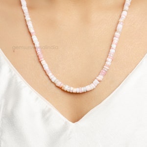 May include: A delicate necklace made of small, pink and white beads. The beads are round and have a slightly iridescent finish. The necklace is approximately 18 inches long.