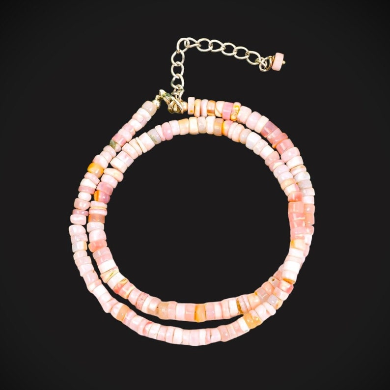 May include: A pink opal beaded necklace with a silver clasp. The necklace is made of small, square-shaped beads.