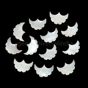 May include: A collection of 13 white mother of pearl crescent moon shaped cabochons. The cabochons are faceted and have a pearlescent sheen.