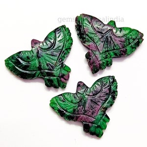 May include: Three green and purple carved gemstone bird pendants. The birds are carved in a detailed design with intricate patterns.