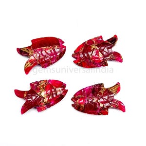 May include: Four red ruby fish carvings with gold accents. The fish are carved in a detailed style and have a glossy finish.