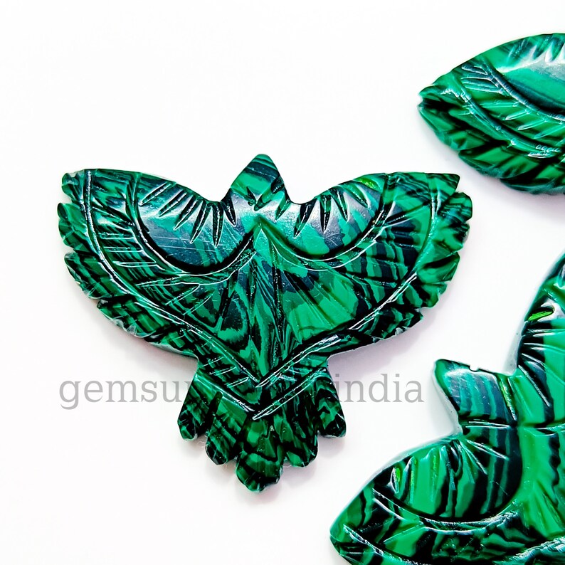 May include: Green malachite stone carved into the shape of a bird with intricate details. The stone has a natural marbled pattern.