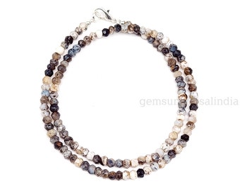 May include: A multi-colored gemstone necklace with a silver clasp. The necklace is made of small, faceted beads in shades of white, gray, brown, and black.