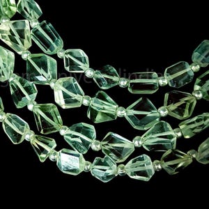 Puede incluir: Una hebra de cuentas de piedras preciosas facetadas de color verde claro. Las cuentas están enhebradas en un alambre de plata.