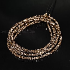 May include: A strand of brown rough diamond beads. The beads are small and irregular in shape, giving the strand a rustic look.