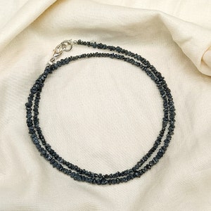 May include: A black diamond necklace with a silver clasp. The necklace is made of small, rough-cut black diamonds.