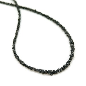 May include: A black diamond necklace made of small, rough-cut stones. The necklace is strung on a thin silver chain.