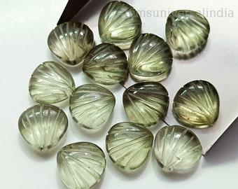 Puede incluir: Una colección de 12 cabujones de piedra preciosa verde tallados en forma de concha. Los cabujones son facetados y tienen una apariencia translúcida.