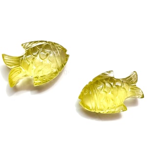 May include: Two yellow carved crystal fish figurines. The fish are detailed with scales and fins.
