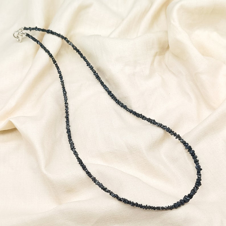 May include: A black diamond necklace made of small, rough-cut stones. The necklace is strung on a silver chain and has a simple clasp.