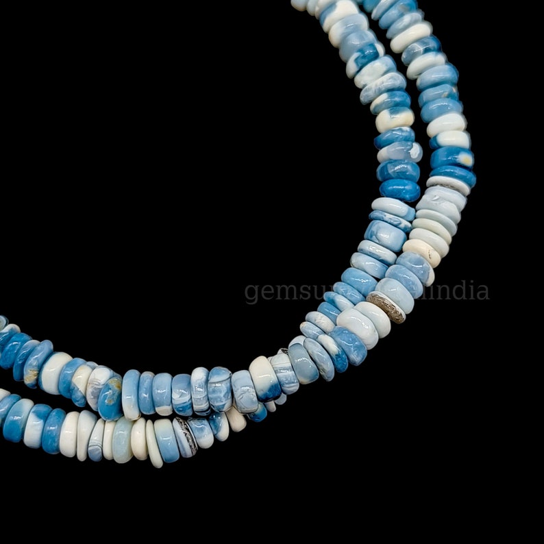 May include: A strand of blue and white opal beads. The beads are round and have a smooth, polished finish. The beads are strung on a clear elastic cord.