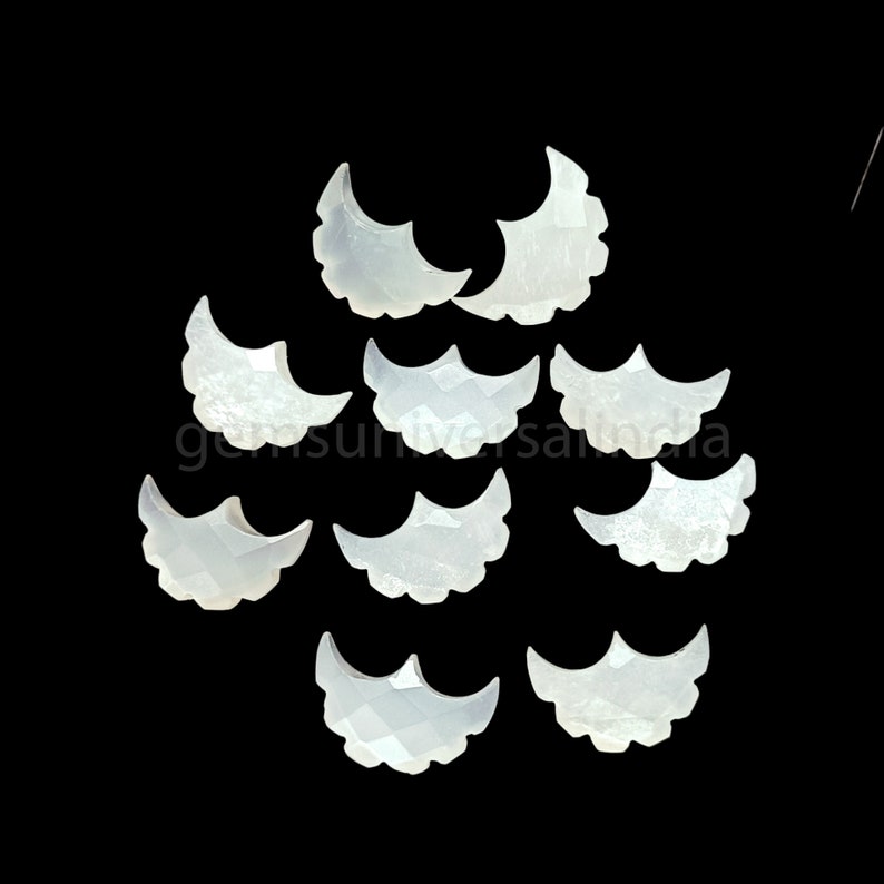 May include: Ten white, crescent-shaped, mother of pearl cabochons with scalloped edges.