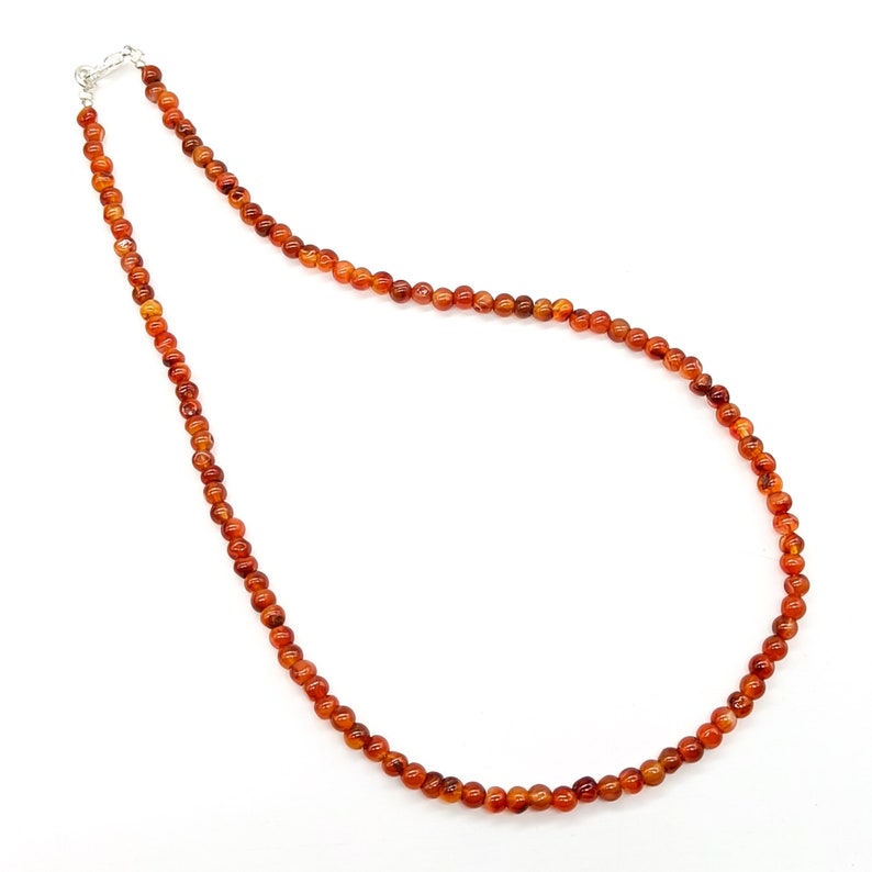 Puede incluir: Un collar de piedras preciosas de cornalina con un cierre de plata. El collar est&aacute; hecho de peque&ntilde;as cuentas redondas.
