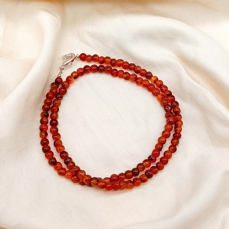 Puede incluir: Un collar de doble cadena hecho de cuentas de cornalina. Las cuentas son de color naranja intenso y est&aacute;n enhebradas en una cadena de plata.