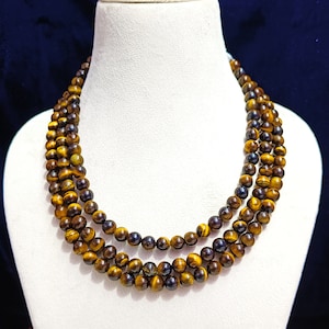 May include: A three-strand necklace made of tiger's eye beads. The beads are a mix of golden brown and dark brown colors.