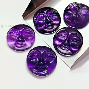 Könnte beinhalten: Fünf violette Amethyst-Cabochons, die in die Form eines Gesichts mit geschlossenen Augen geschnitzt sind. Die Cabochons werden auf einem silbernen Tablett präsentiert.