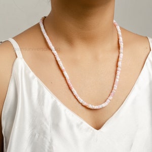 May include: A delicate necklace made of small, pale pink and white opal beads. The necklace is strung on a thin, silver chain and is approximately 18 inches long.