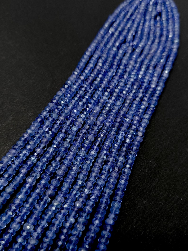 K&ouml;nnte beinhalten: Eine Str&auml;hne blauer Edelsteinperlen. Die Perlen sind facettiert und haben eine leicht unregelm&auml;&szlig;ige Form. Die Perlen sind auf einem durchsichtigen Faden aufgef&auml;delt.