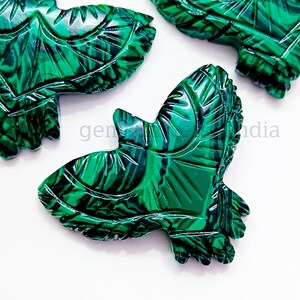 May include: Green malachite stone carved into the shape of a bird. The bird has intricate details and a swirling pattern.