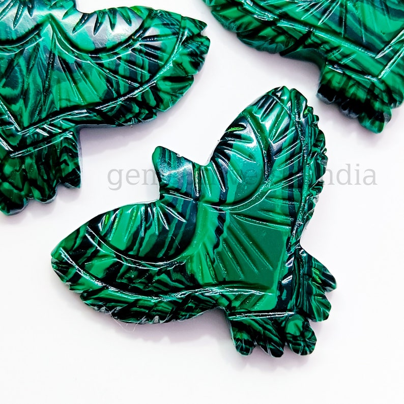 May include: Green malachite stone carved into the shape of a bird. The bird has intricate details and a swirling pattern.