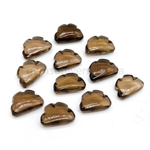 Pode incluir: Doze cabochões de quartzo fumado marrom, cada um esculpido em forma de nuvem. Os cabochões são lisos e polidos, com uma aparência translúcida.