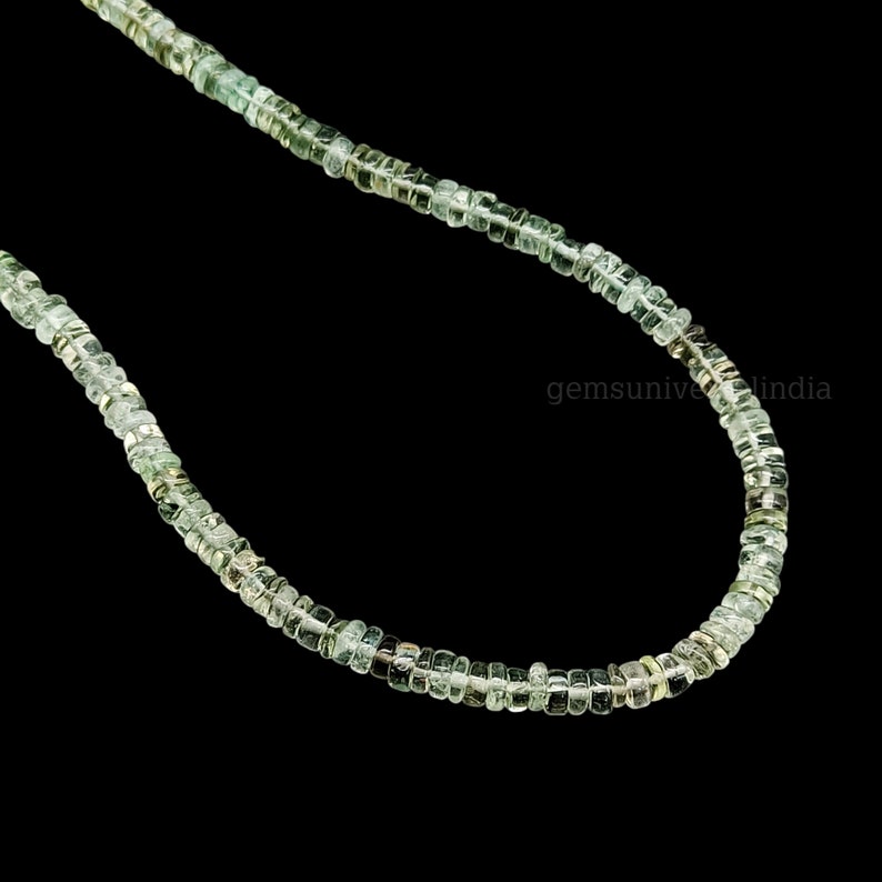 May include: A strand of light green gemstone beads, strung on a thin wire. The beads are faceted and have a slightly irregular shape.