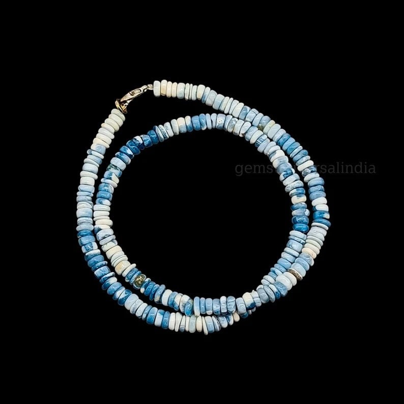 May include: A strand of blue and white opal beads, with a silver clasp. The beads are small and round, and the necklace is approximately 18 inches long.