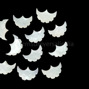 May include: A collection of 10 white mother of pearl crescent shaped cabochons. The cabochons are all approximately the same size and shape, and they have a smooth, polished surface.