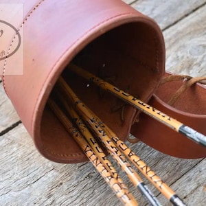 May include: A brown leather quiver with visible stitching and a leather strap, containing several wooden arrows with the word VINTAGE printed on the shafts. The logo gw leathercraft is visible in the upper left corner of the image.