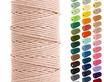 May include: A spool of thick, natural cotton rope in a light pink color. The rope is wound tightly around the spool, creating a smooth, even surface. The spool is made of wood and has a natural finish.