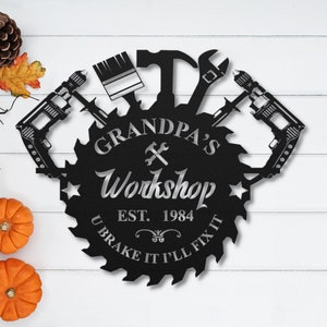 May include: Black metal sign shaped like a saw blade with the text "Grandpa's Workshop Est. 1984 U Brake It I'll Fix It" and various tools including a paintbrush, hammer, wrench, and drills.