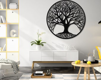 May include: Black metal wall art featuring a tree of life design. The tree is surrounded by a circle and has intricate branches and roots. The art is hanging on a white wall above a white dresser and a wooden coffee table.