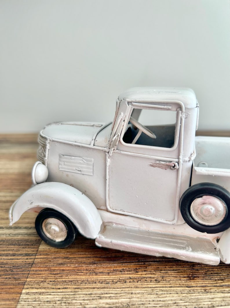 A white vintage-style truck is displayed on a wooden surface.