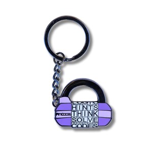 May include: Purple metal keychain shaped like a padlock with the words "LOGIC", "HINTS", "THINK", "SOLVE", and "CODES" printed on it.
