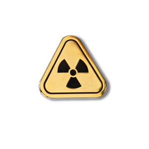 May include: A yellow triangular warning sign with a black radiation symbol inside. The sign is made of metal and has a shiny finish.