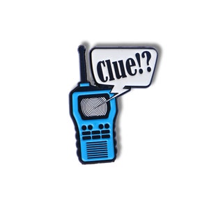 Puede incluir: Pin de esmalte azul y negro de un walkie-talkie con una burbuja de diálogo que dice "Clue!?"