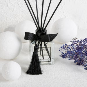 May include: Black and white diffuser bottle with a black tassel and bow. The bottle is labeled "JARDEN Authentic Home Fragrance".