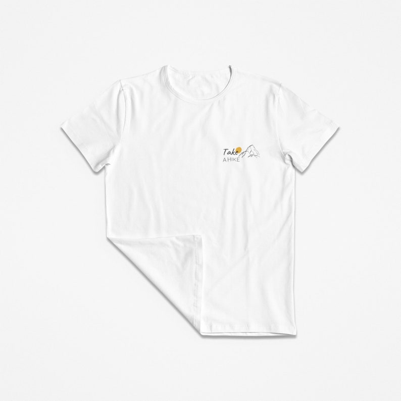 May include: White t-shirt with a simple graphic design of a mountain with a sun and the text "Take a Hike".